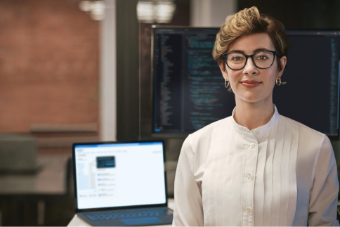 A person stands in front of a laptop and a desktop computer.