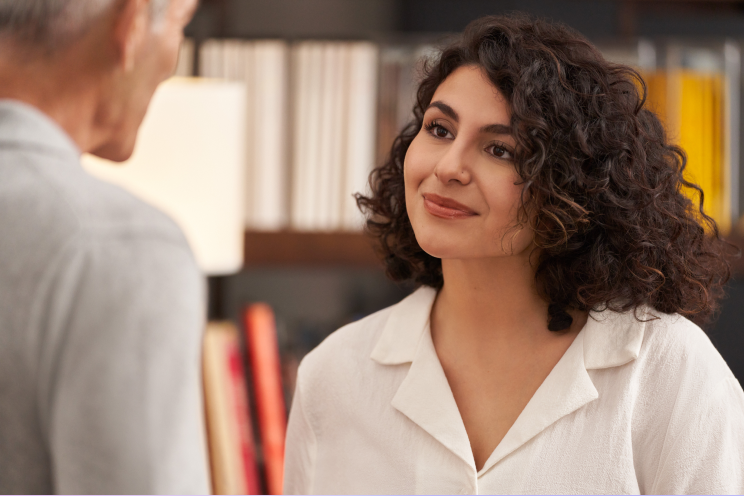 Two people talk in a library.